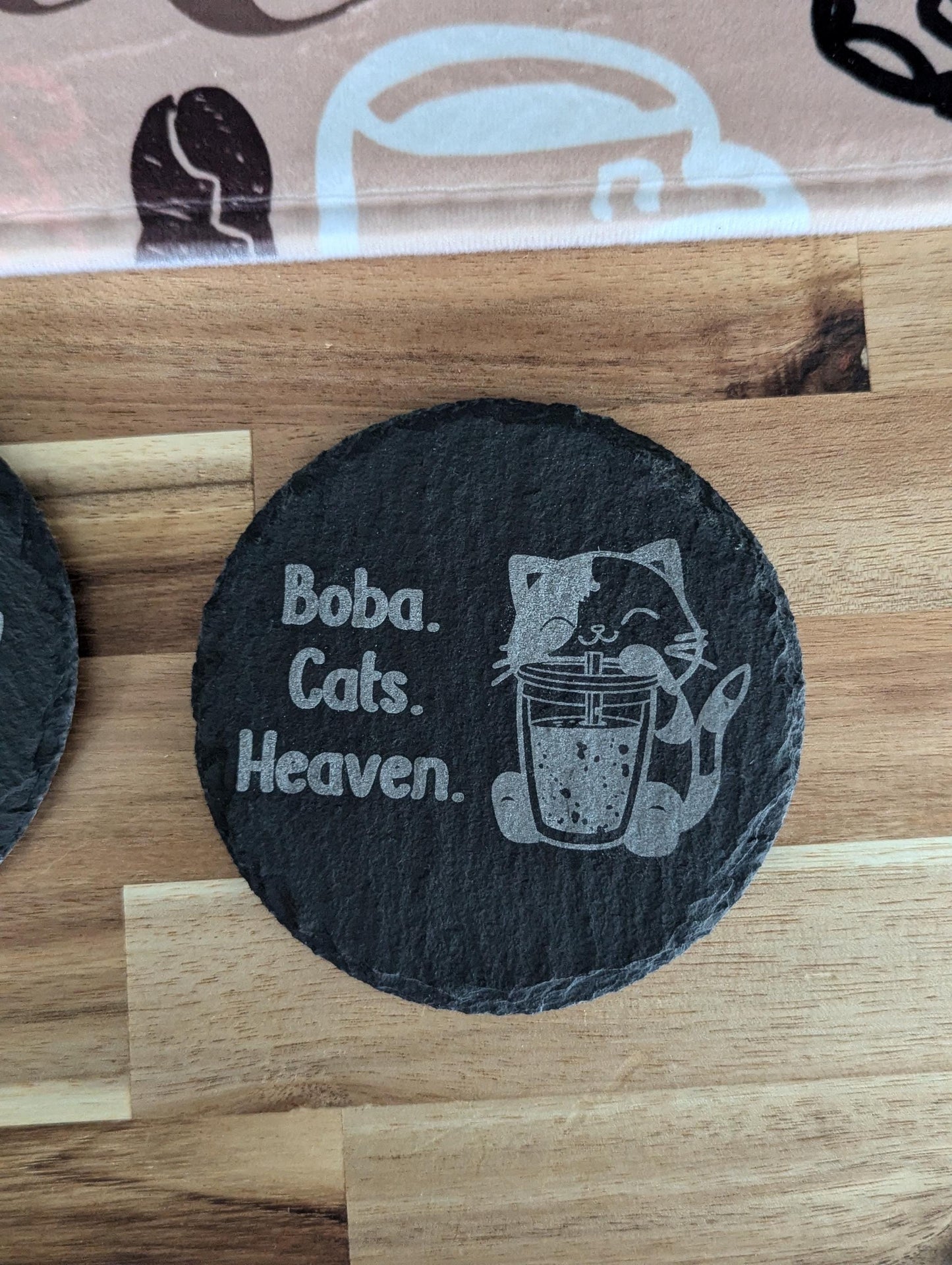 Slate coaster with a laser-engraved design of a cute cat sipping boba alongside text that says boba, cats, heaven.