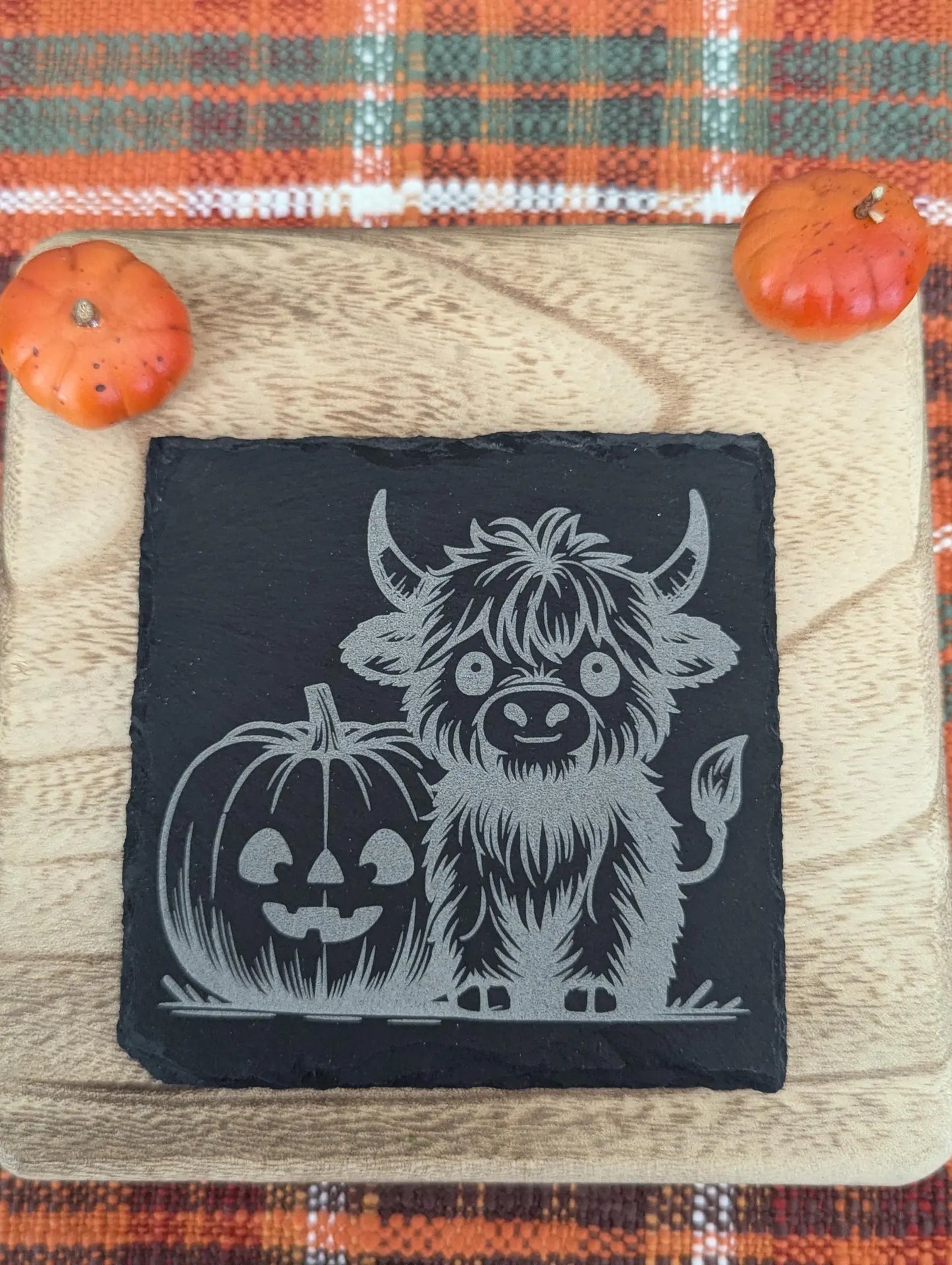 Slate coaster engraved with a highland cow and a pumpkin with fall decor.