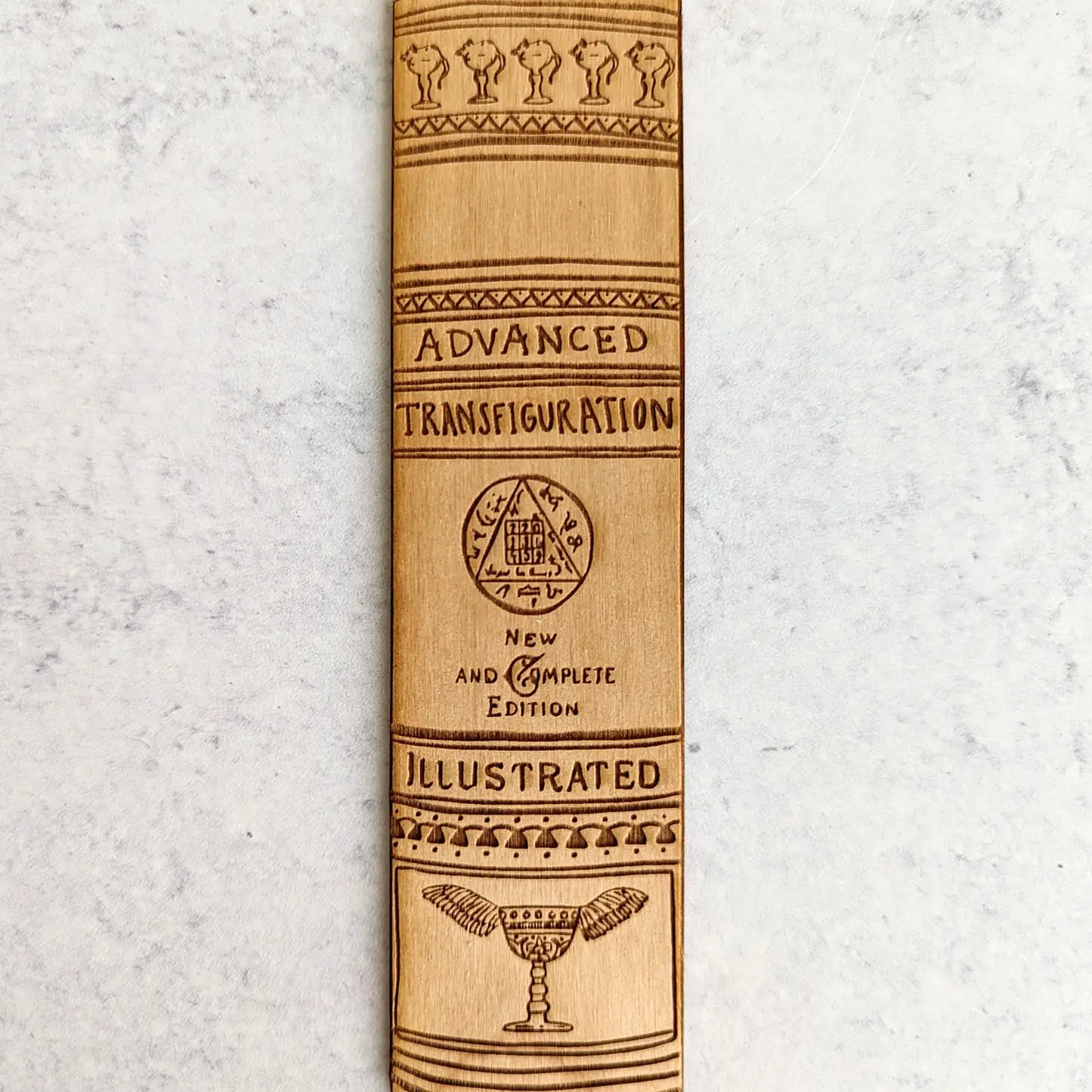A wooden bookmark that says "Advanced Transfiguration. New and Complete Edition. Illustrated."