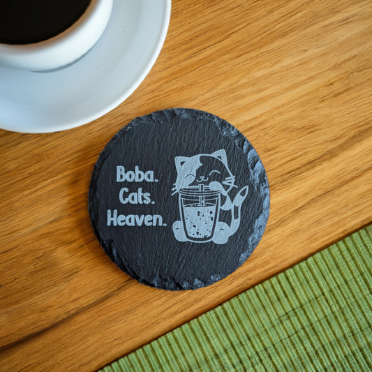 Slate coaster with a laser-engraved design of a cute cat sipping boba alongside text that says boba, cats, heaven.