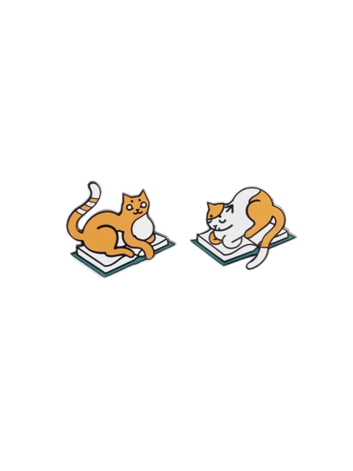 Two pins of orange-and-white cats laying on books.