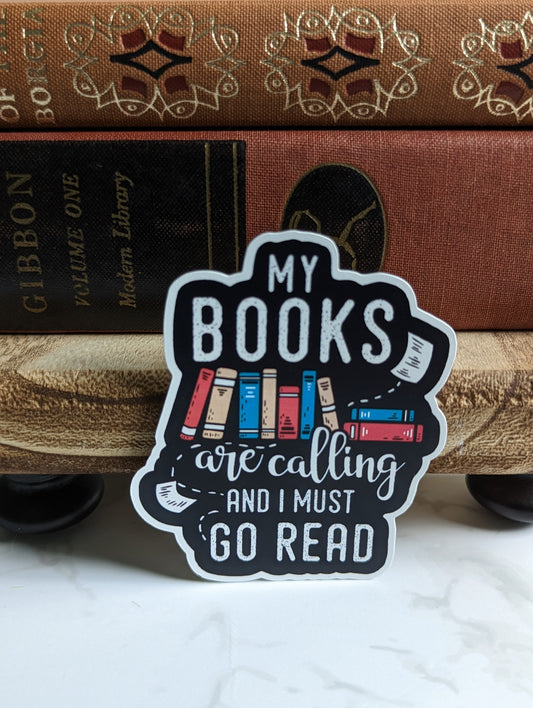A sticker that says "My books are calling and I must go read". In between are some books.